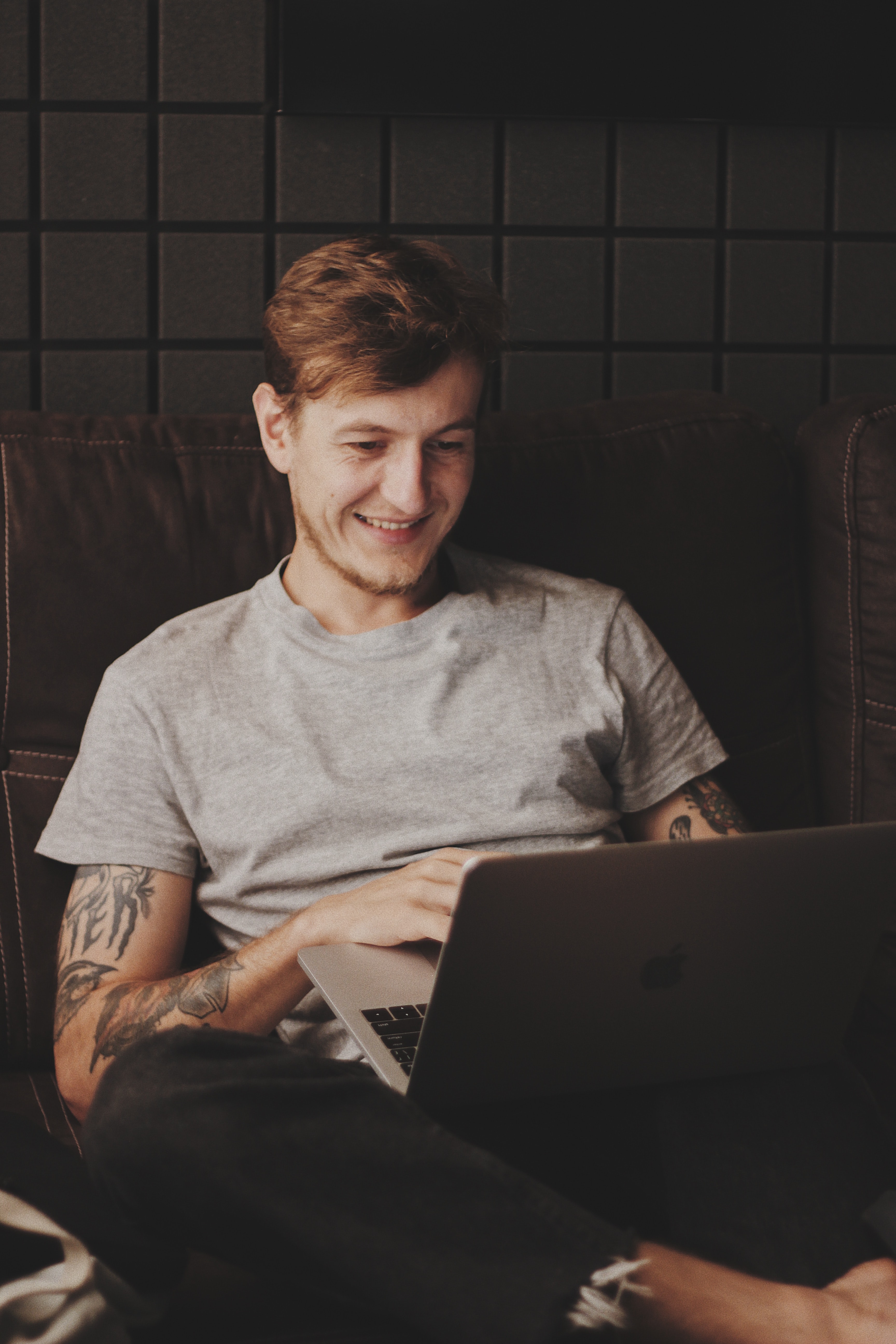 Junger Mann arbeitet mit Laptop im Sitzen